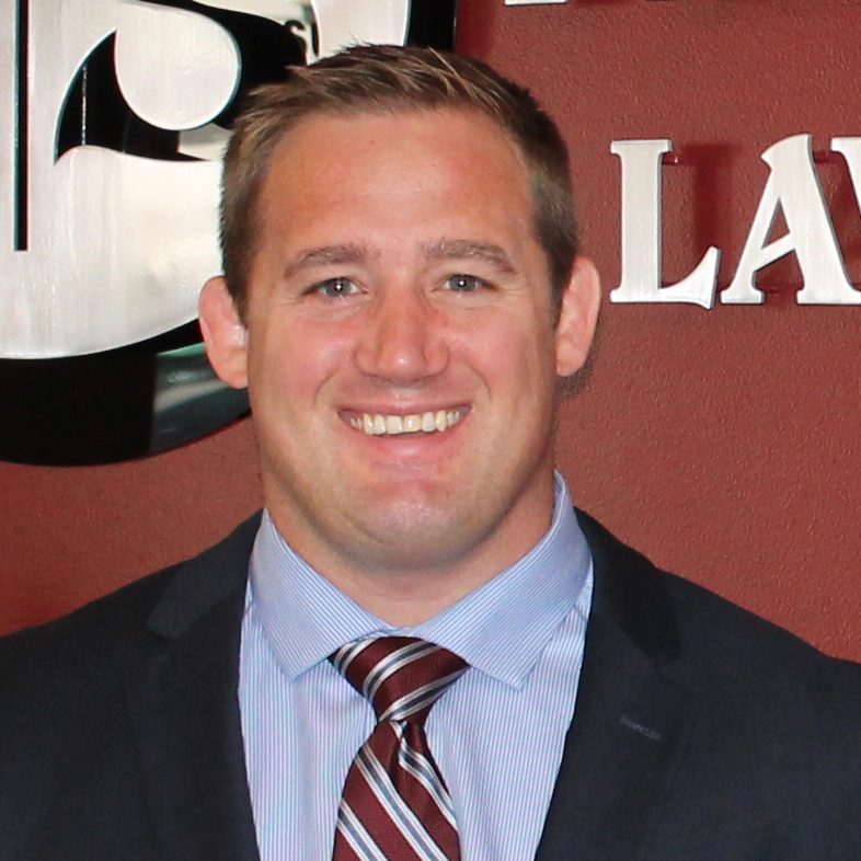 A man in suit and tie standing next to a wall.