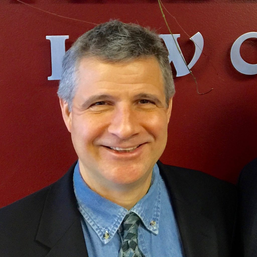 A man in a suit and tie smiling for the camera.