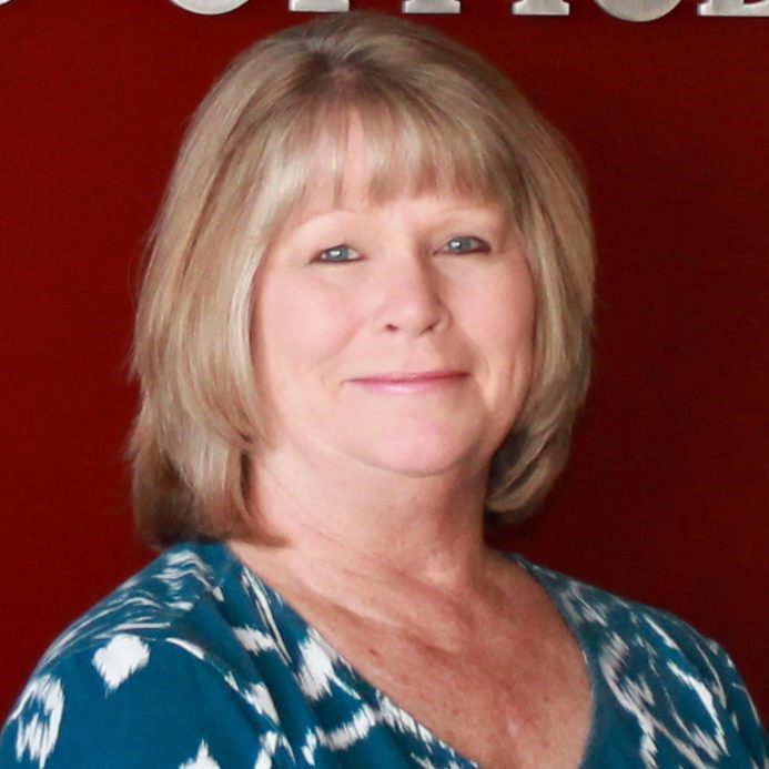 A woman standing in front of the office sign.