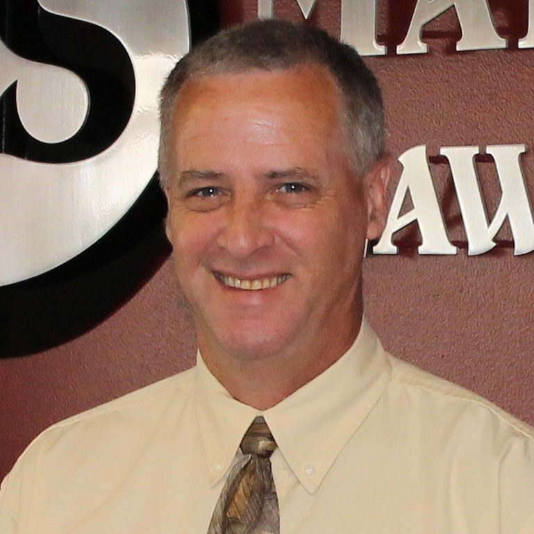 A man in a white shirt and tie standing next to a wall.