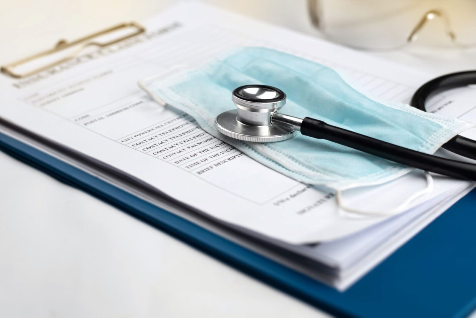 A stethoscope and mask on top of papers.